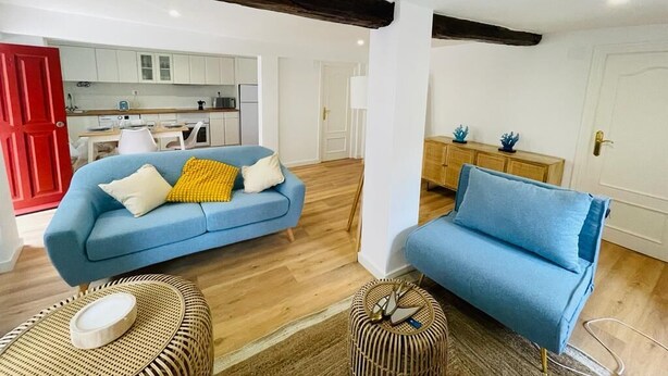 Ein Wohnzimmer mit einem blauen Sofa, einem Korbsessel und Holzboden.