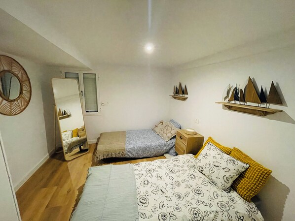 Une chambre à coucher avec un lit, une table de chevet, un miroir et des objets décoratifs accrochés au mur.