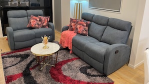 A modern living room with two grey sofas, a small round table, and a patterned rug.