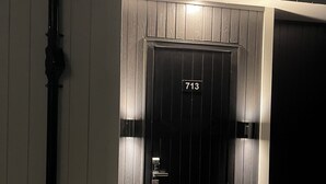 A black door with the number 713, a metal handle, and a small light above it.