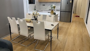 A modern kitchen with a dining area, featuring a marble countertop, stainless steel appliances, and a minimalist design.