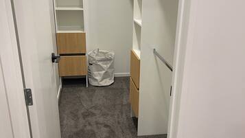 A walk-in closet with open shelves, a wooden cabinet, and a trash bag on the floor.