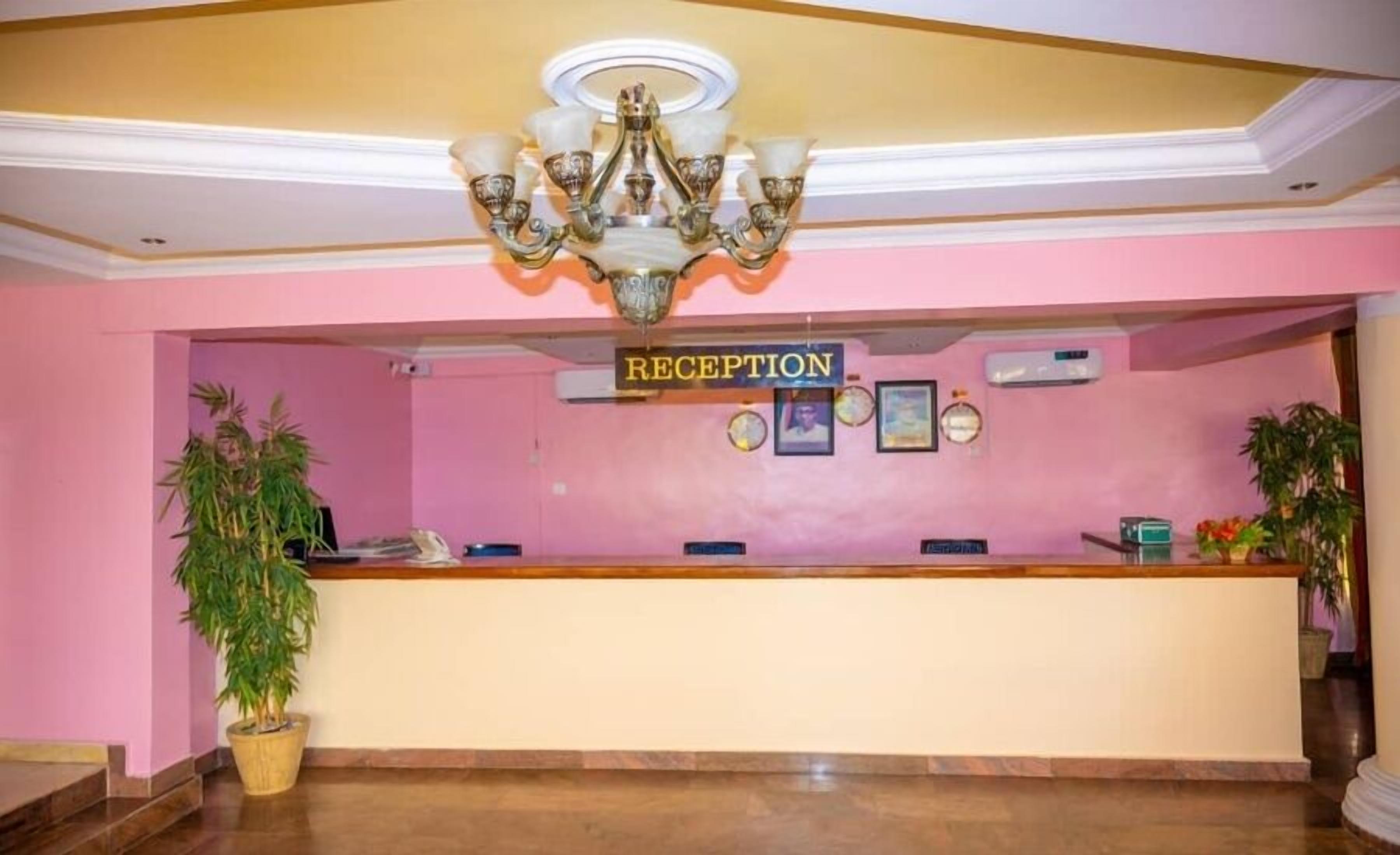 Un área de recepción con un cartel que dice "RECEPTION", una araña y plantas en macetas.