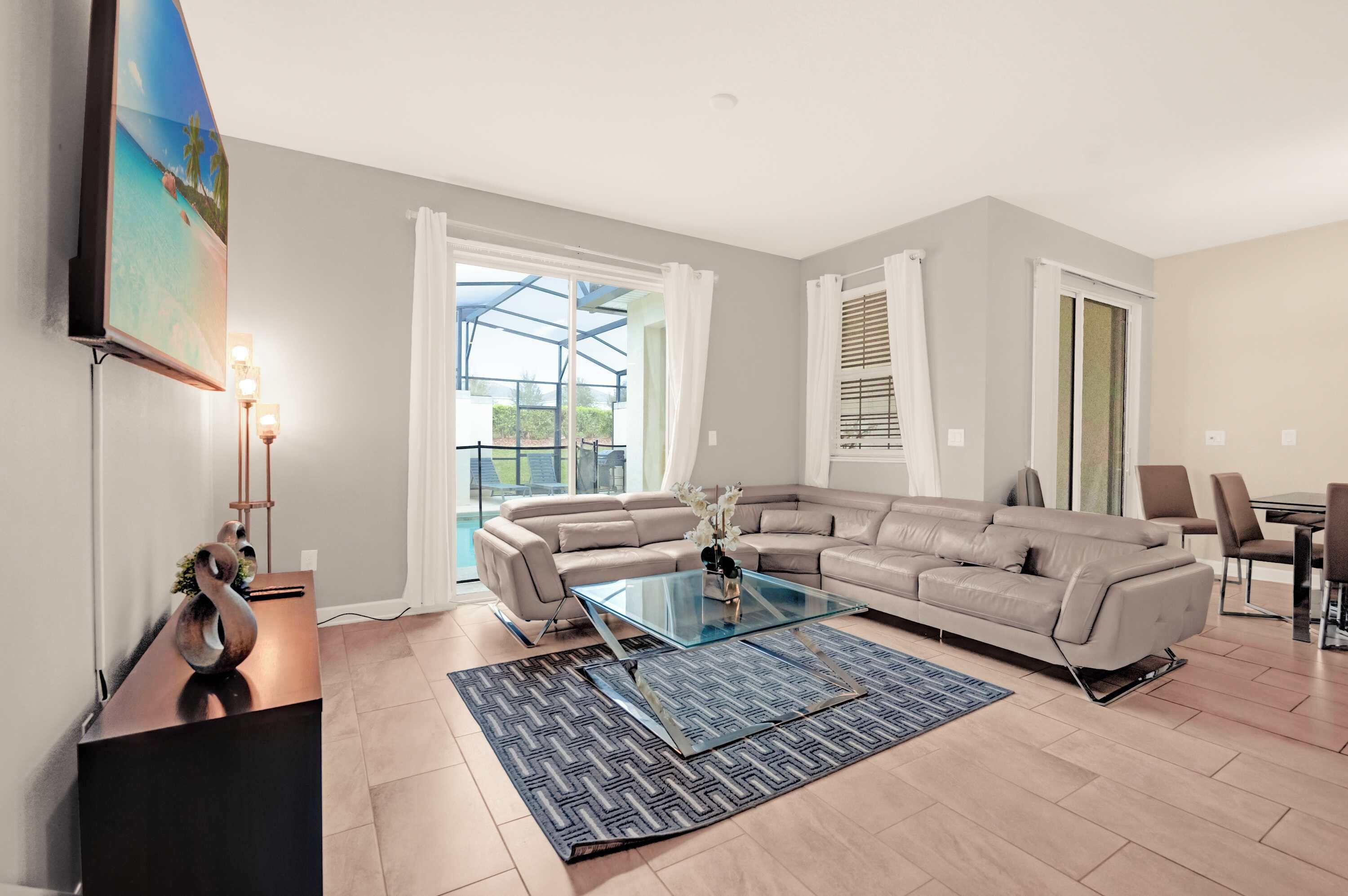 Relax in this spacious living room with a modern sectional sofa and easy access to the pool area for a perfect blend of comfort and leisure.