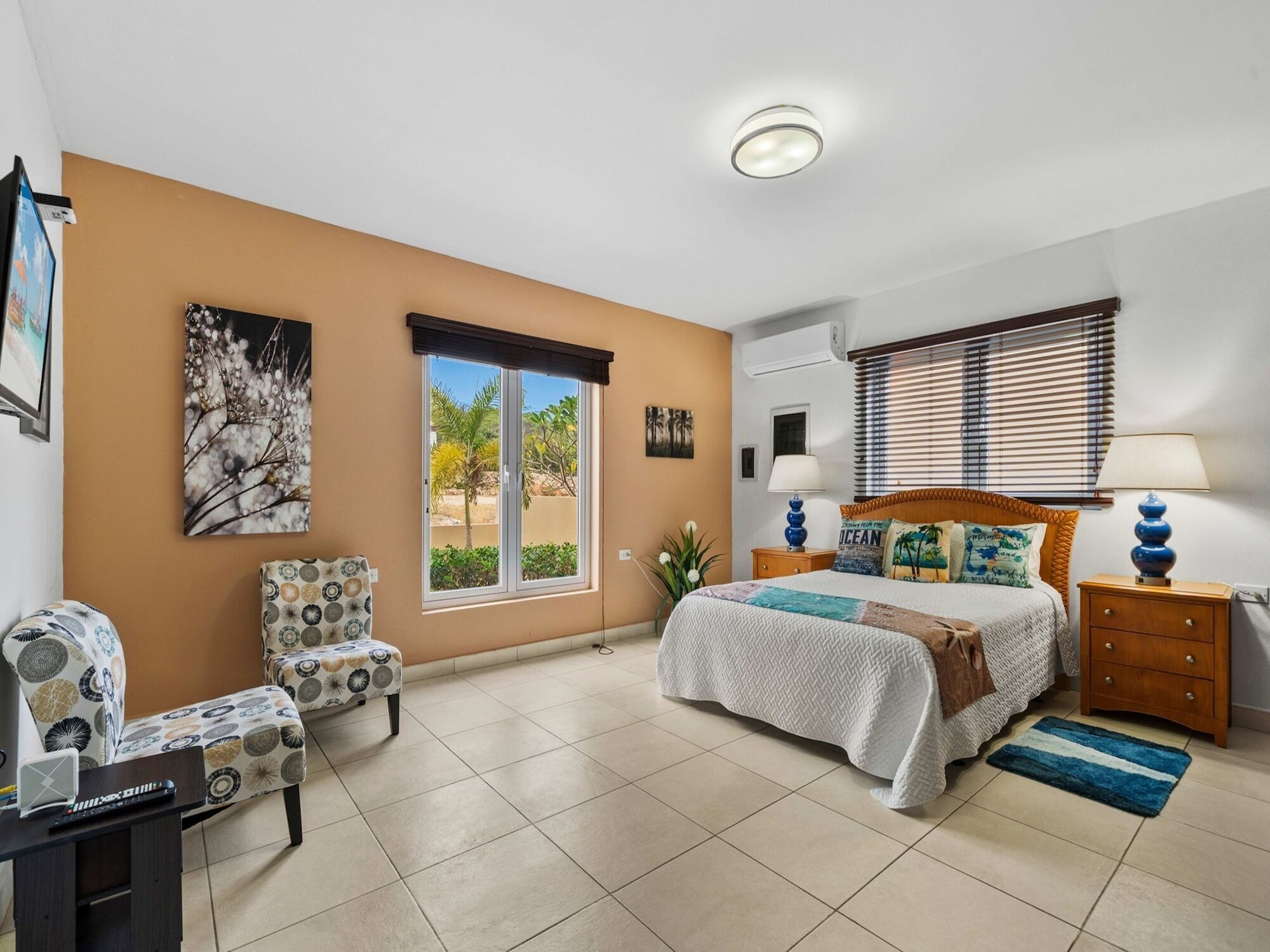 A bedroom with a bed, a chair, a nightstand, a lamp, a window, and a painting.