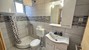 A modern bathroom with a toilet, bidet, sink, and a shower with a towel hanging. - Studio apartman Easy (Crikvenica)