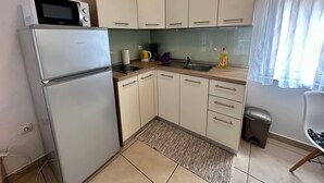 A compact kitchen with a refrigerator, microwave, and a sink. - Studio apartman Easy (Crikvenica)