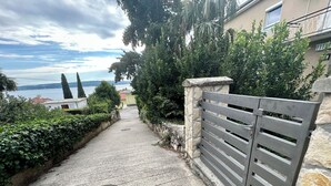 A paved pathway leading to a gated entrance with a stone wall and metal gate. - Studio apartman Easy (Crikvenica)