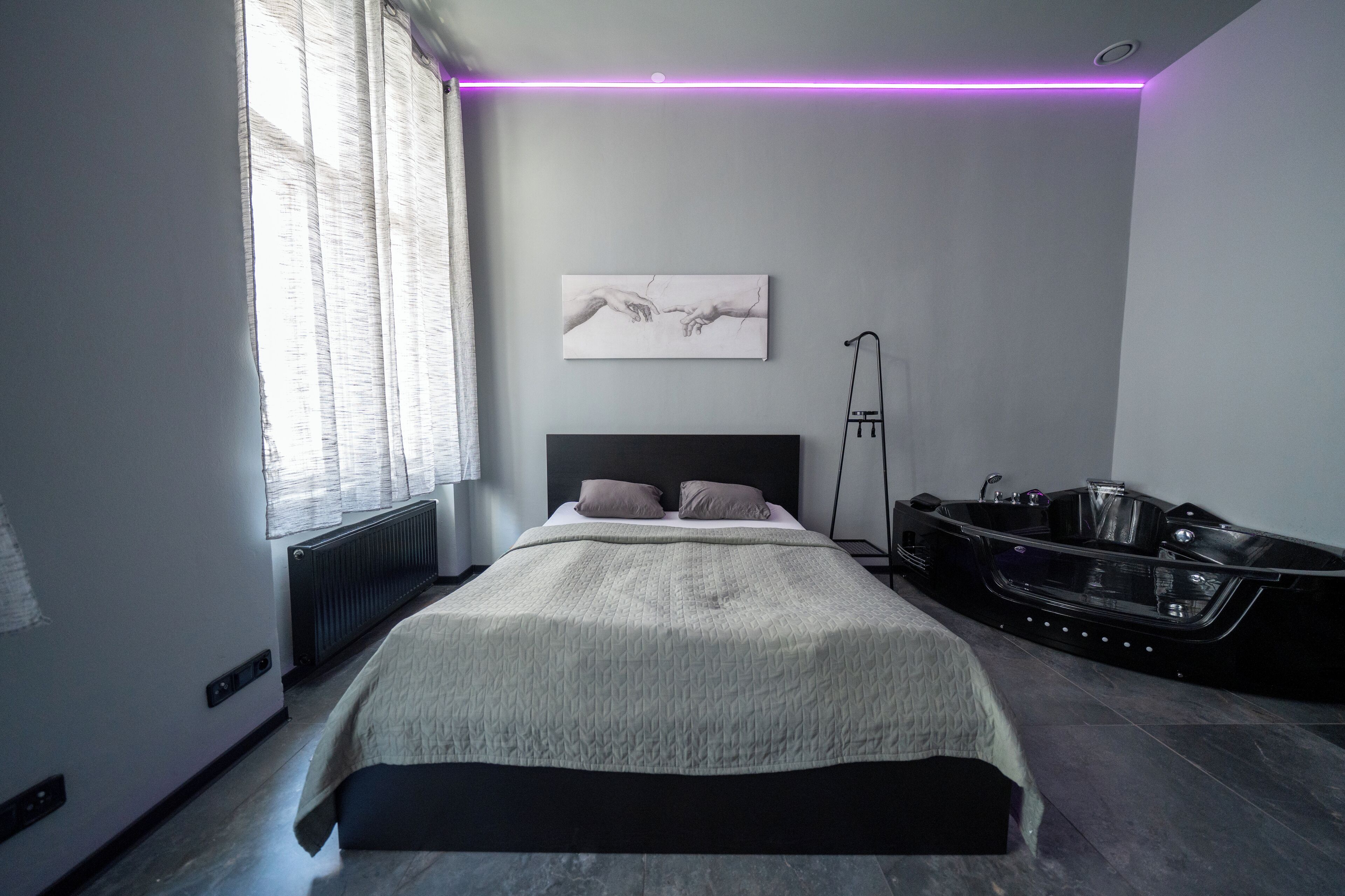 A modern bedroom with a bed, a bathtub, and a radiator.
