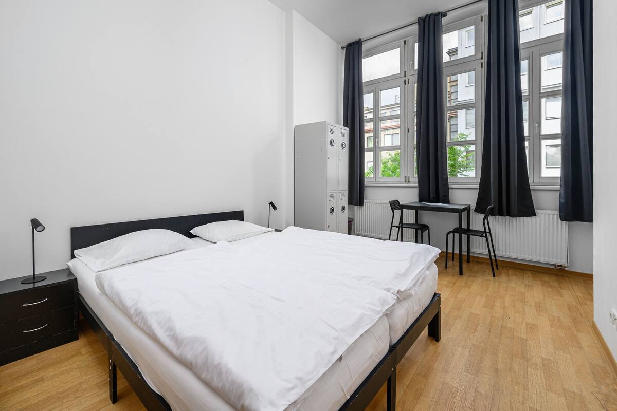 Un dormitorio con cama, escritorio, silla, armario y radiador.