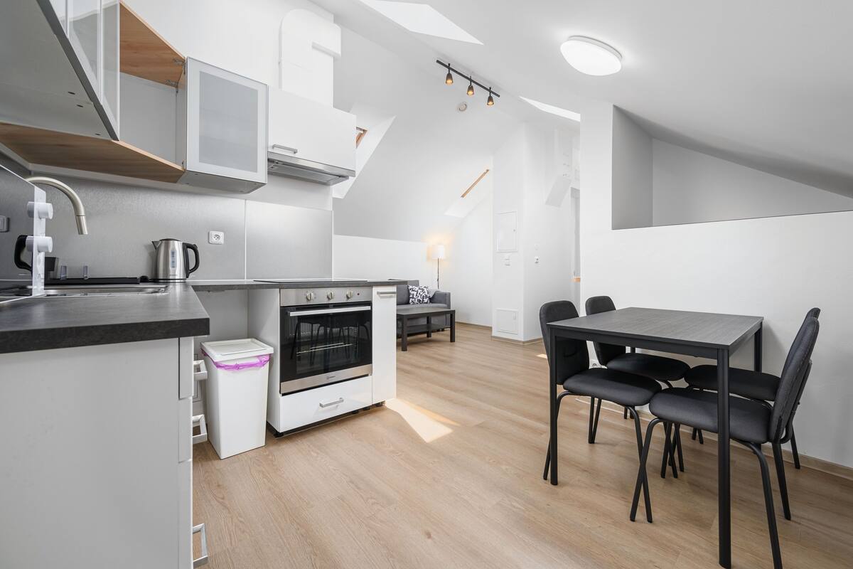 Una cocina moderna con horno integrado, cafetera y comedor con mesa y sillas.