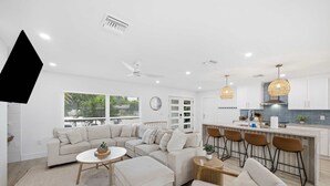 A modern living room with a sectional sofa, a coffee table, and a dining area with bar stools.