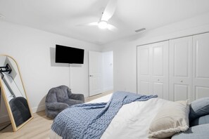 Een slaapkamer met een bed, een stoel, een televisie en een kledingkast.