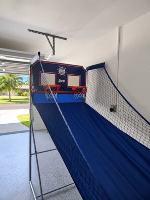 Una cancha de baloncesto con piso azul, dos aros y redes.