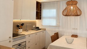 A modern kitchen with white cabinetry, a built-in oven, and a dining area with a table and chairs. - Apartment with terrace and sea view - 3 bedrooms - Llançà (Cap de Creus) (Llançà)