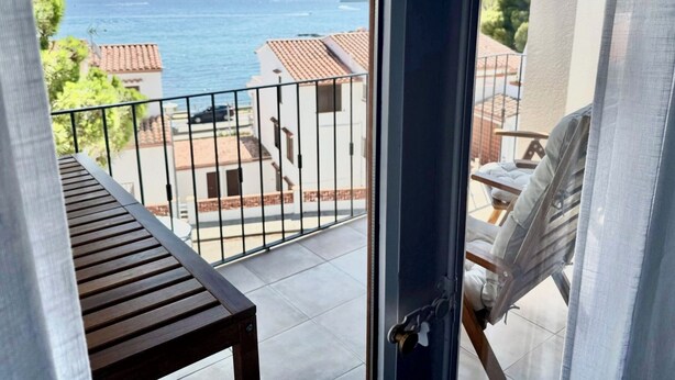 En balkon med udsigt over havet og bygninger.