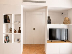 A modern living room with a flat-screen TV, a bookshelf with books and decorative items, and a white wardrobe. - Apartment with terrace and sea view - 3 bedrooms - Llançà (Cap de Creus) (Llançà)