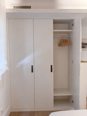 Ein weißer Kleiderschrank mit zwei Türen und einer Kleiderstange.