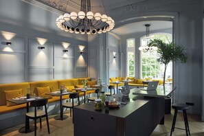 Un espace repas moderne avec un îlot central, des sièges jaunes et des luminaires suspendus.