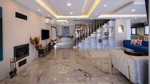 A modern living room with a marble floor, a blue sofa, a fireplace, and a staircase leading to another level. - Luxury Private Pool Villa in Fethiye6En-Suite Bedrooms Sleeps12  Sea&Nature View (Mugla)