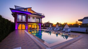 A modern house with a swimming pool, lounge chairs, and a well-lit patio area. - Luxury Private Pool Villa in Fethiye6En-Suite Bedrooms Sleeps12  Sea&Nature View (Mugla)