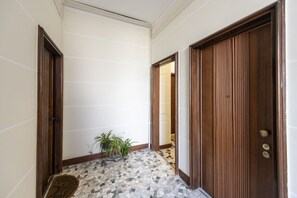 A hallway with a tiled floor, wooden doors, and a potted plant. - Argonne, 51 – Spazio Argonne: studio apartment (Milano)