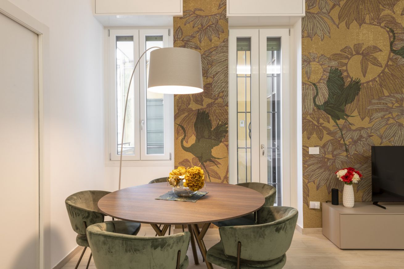 Un coin repas comprenant une table ronde, quatre chaises, une lampe et un téléviseur.