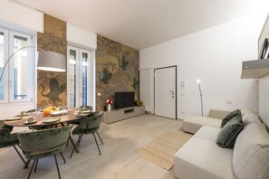 Ein modernes Wohnzimmer mit Essbereich, einer Couch, einem Fernseher und einer Wand mit Muster.