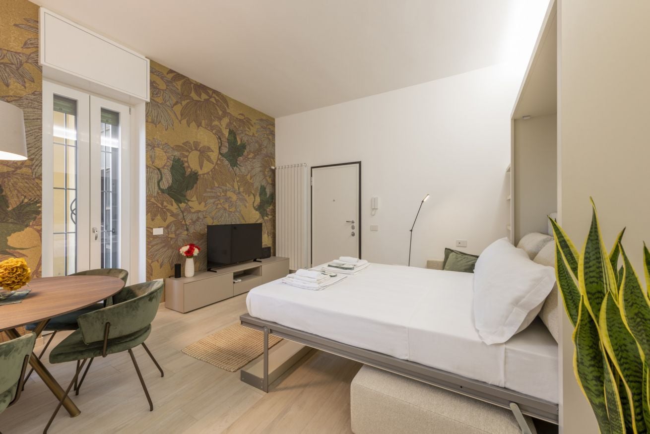 Ein modernes Hotelzimmer mit Bett, Schreibtisch, Fernseher und einem großen Fenster.