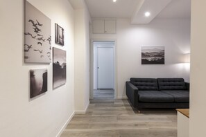 Ein modernes Interieur mit einem grauen Sofa, Kunstwerken an den Wänden und Holzboden.