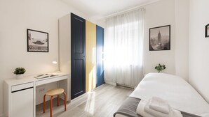 Een moderne hotelkamer met een bed, bureau, stoel en een groot raam met gordijnen.