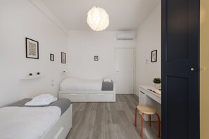 Ein modernes Schlafzimmer mit Bett, Schreibtisch und Stuhl, einer Hängelampe und einer Tür.