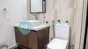 Een moderne badkamer met een houten wastafelmeubel, een witte wasbak, een spiegel en een toilet.