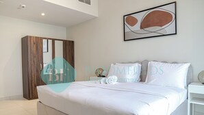 Een moderne slaapkamer met een groot bed, een kledingkast en een abstract schilderij aan de muur.