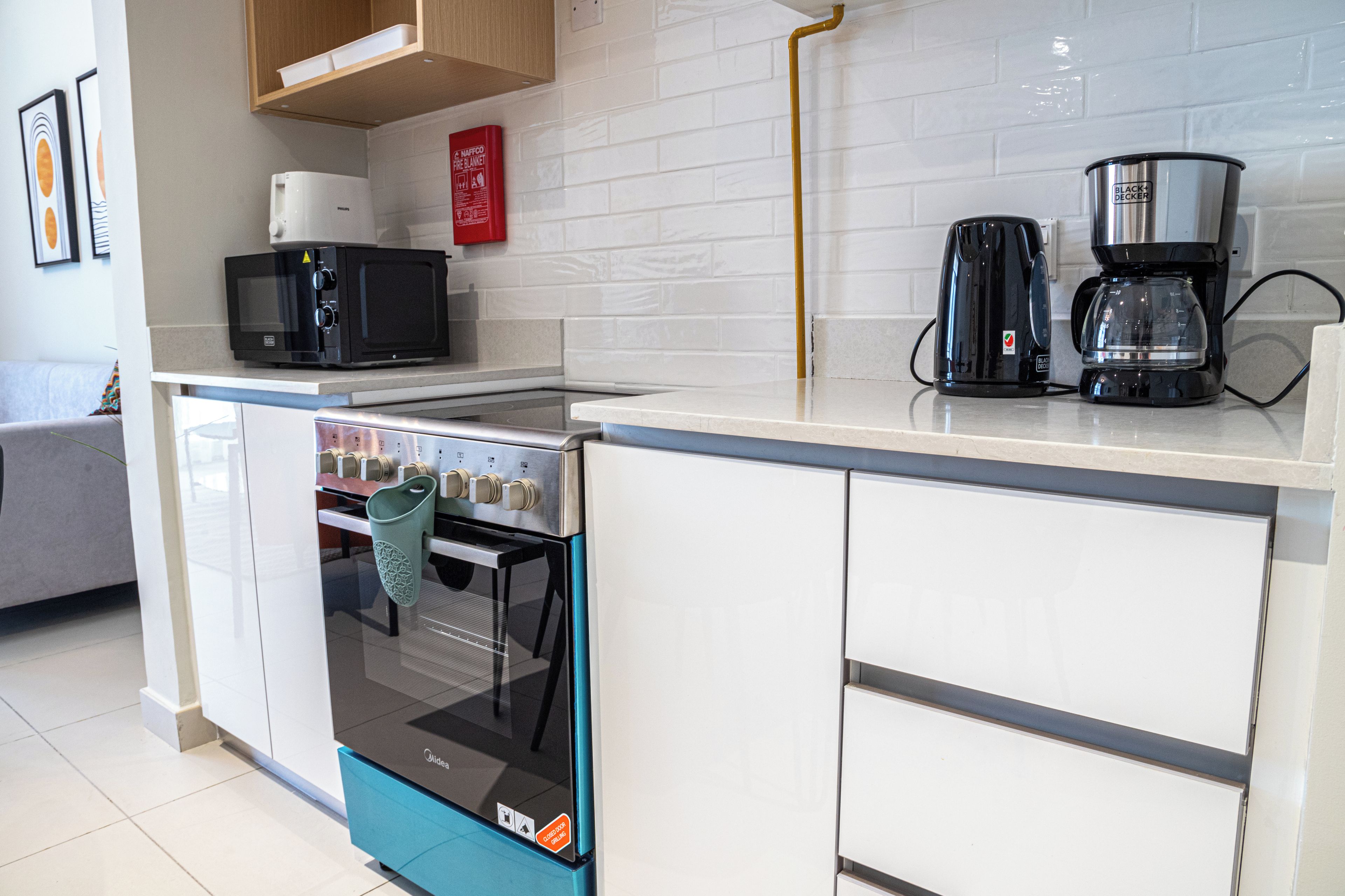 Cozinha compacta com forno embutido, micro-ondas e máquina de café.