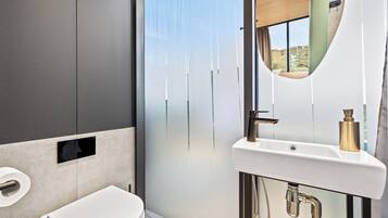 Een moderne badkamer met toilet, wastafel en een groot raam.