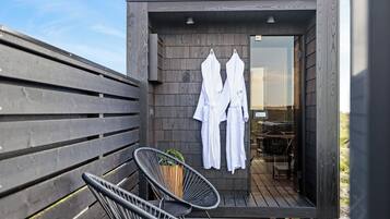 Een modern gebouw met een houten gevel, een glazen deur en twee witte badjassen aan de muur.