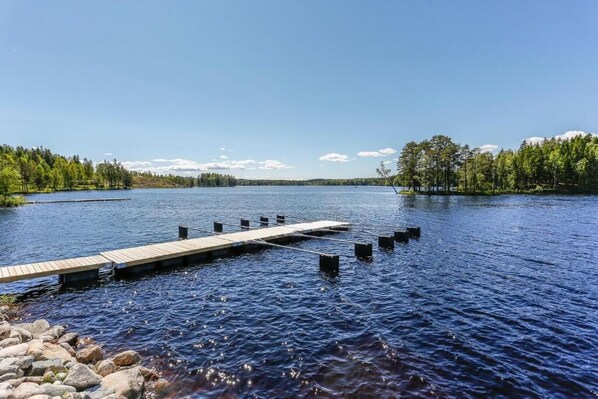 A wooden dock extending into a calm lake surrounded by dense forest. - Lakelodge (Karlskoga)