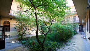 A courtyard with a tree, brick pathway, and buildings with balconies. - St King 11. Studio Apartments (Budapest)