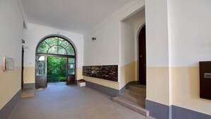 A hallway with a tiled floor, a staircase, and a wall-mounted display case. - St King 11. Studio Apartments (Budapest)