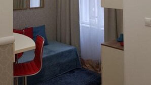 A compact room with a bed, a small desk, a chair, and a window with sheer curtains. - St King 11. Studio Apartments (Budapest)