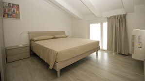 Un dormitorio con cama, mesita de noche y ventana con cortinas.