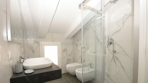 Un baño moderno con una bañera grande, un bidé y una ducha con paredes de vidrio.