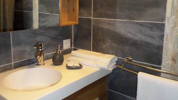 A bathroom with a wooden vanity, a white sink, a towel rack, and a mirror.