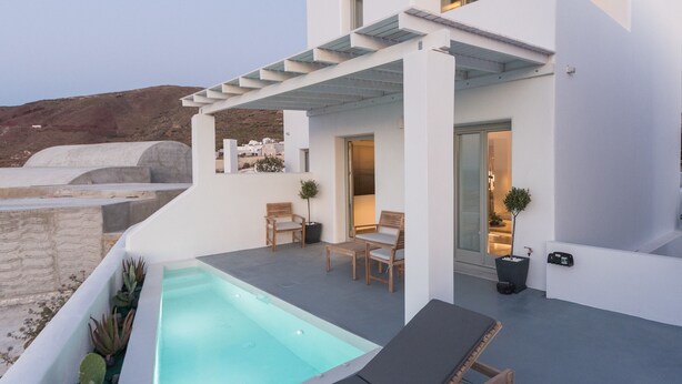Una villa moderna y blanca con piscina, mobiliario de exterior y vistas al paisaje.