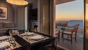 Un comedor con una mesa preparada para dos, un sofá y un televisor al fondo.