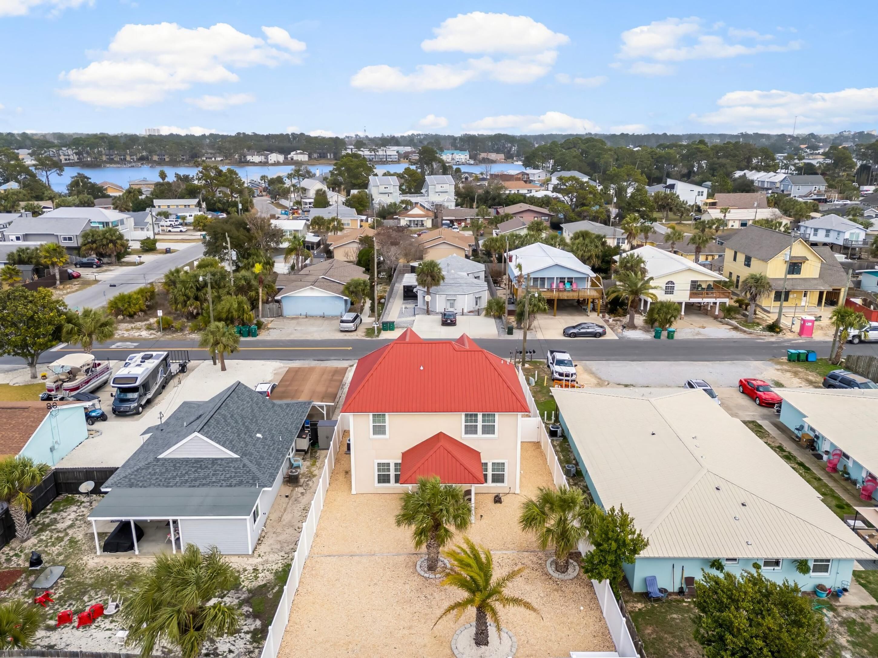 A residential area with houses, a street, and a body of water in the background.