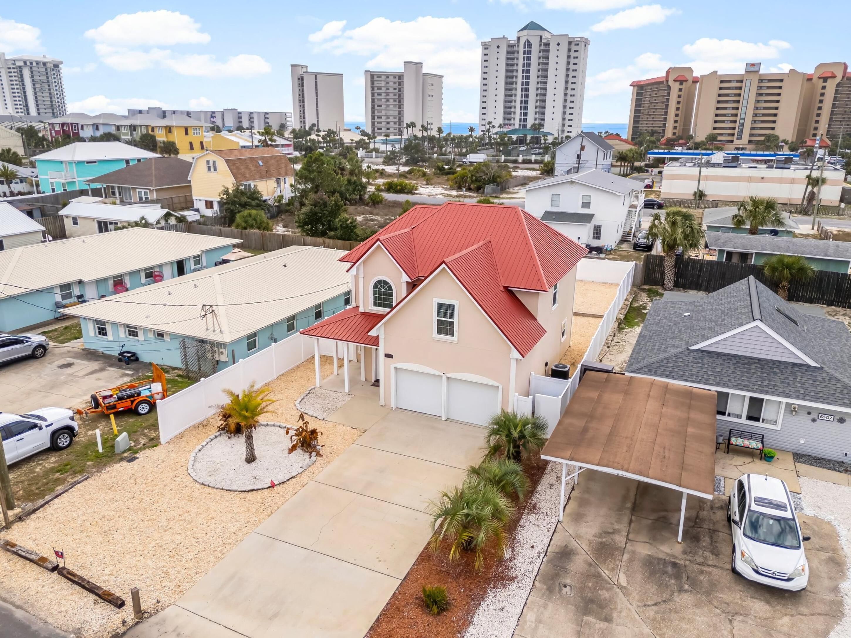 A residential area with houses, a parking lot, and a beach in the background.