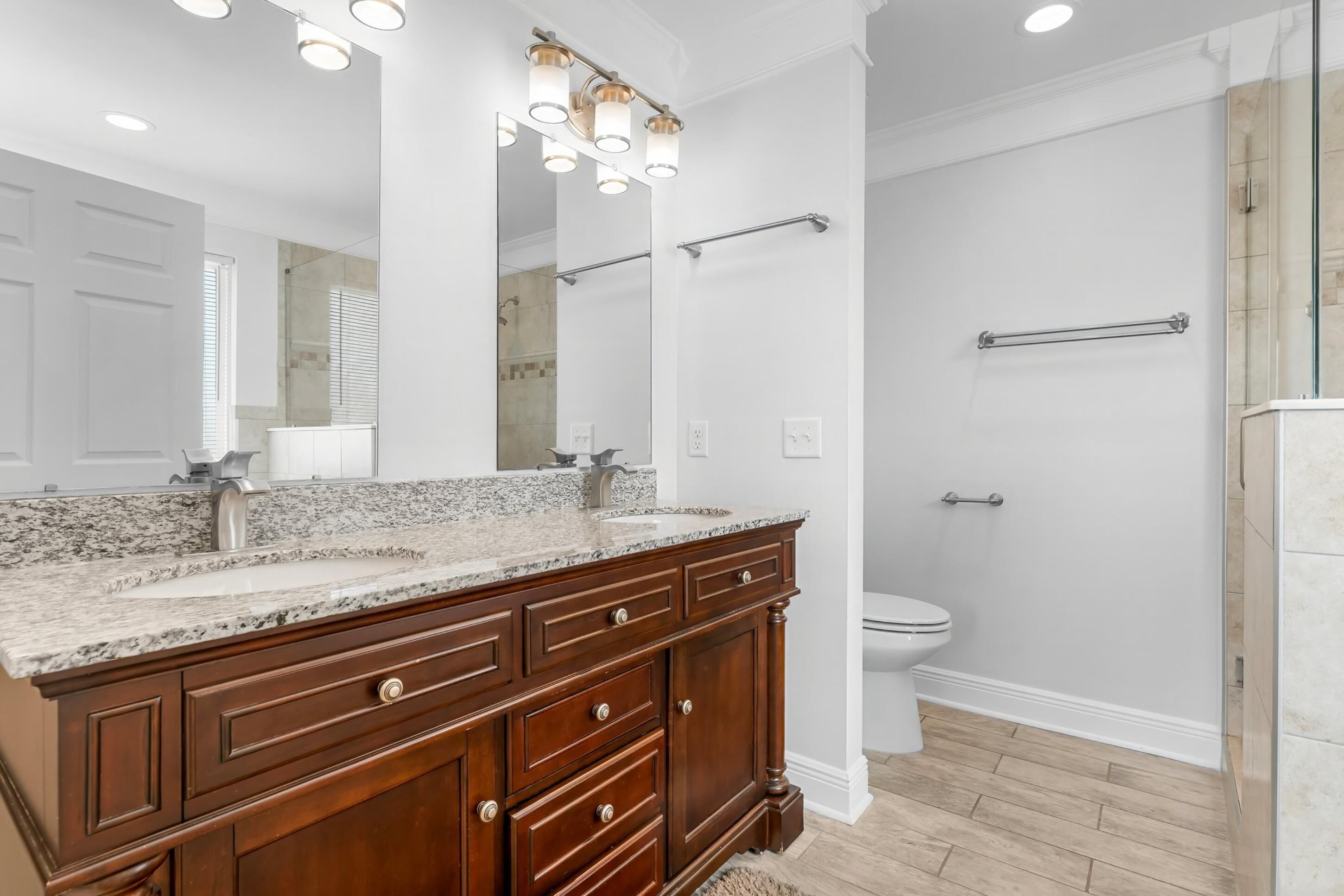 A bathroom with a double vanity, a large mirror, and a shower area.