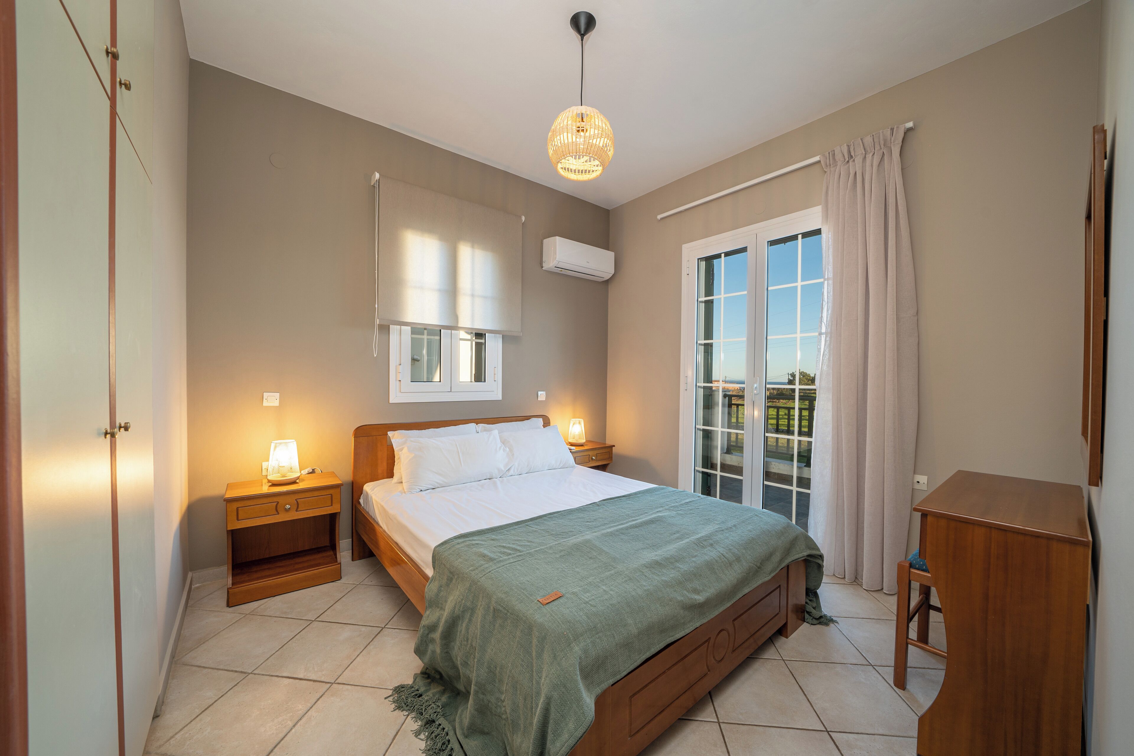 A bedroom with a bed, bedside tables, a window with curtains, and a ceiling light.